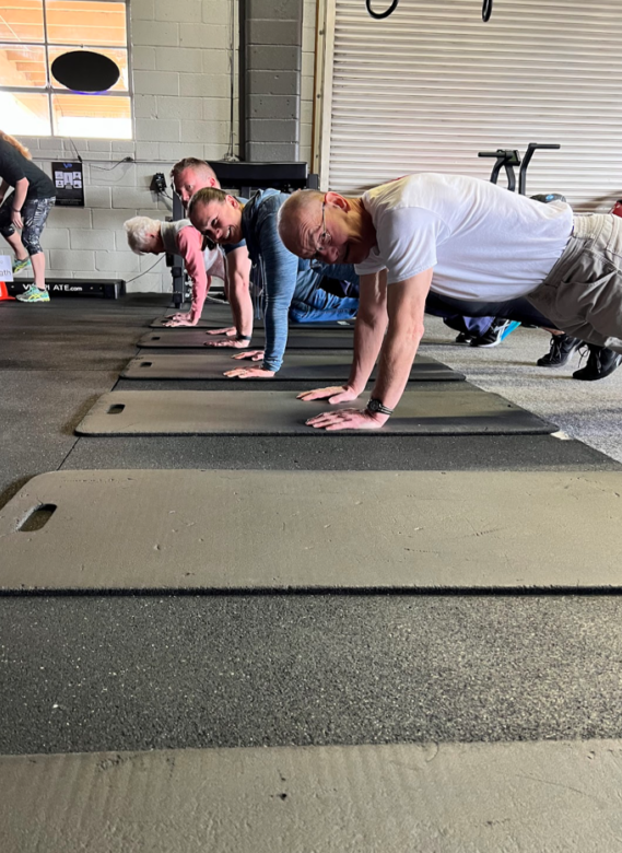 a group of people doing push ups in a gym.