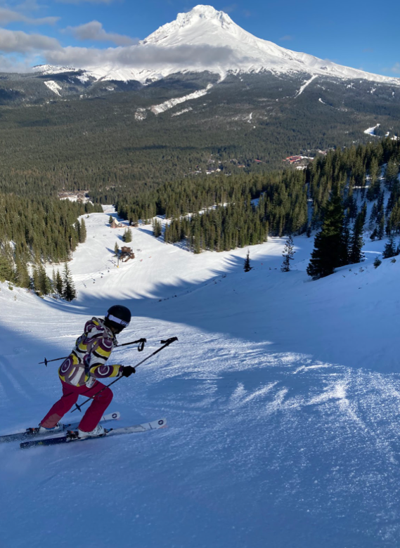 a person skiing down a snowy slope with a mountain in the background.