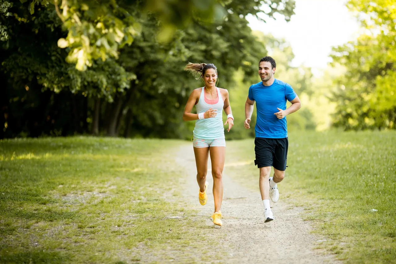 a man and woman jogging in a park.