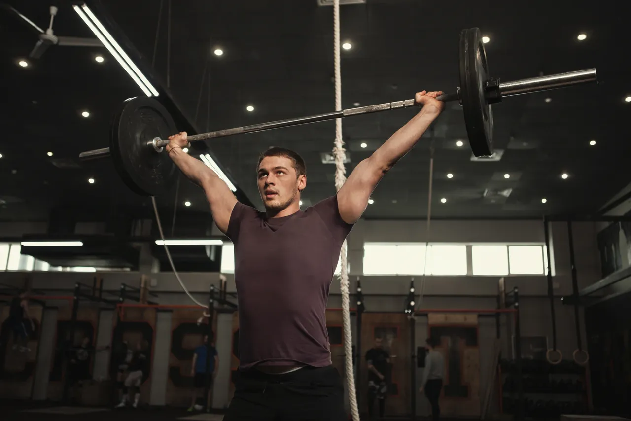 a man lifting a barbell in a gym.